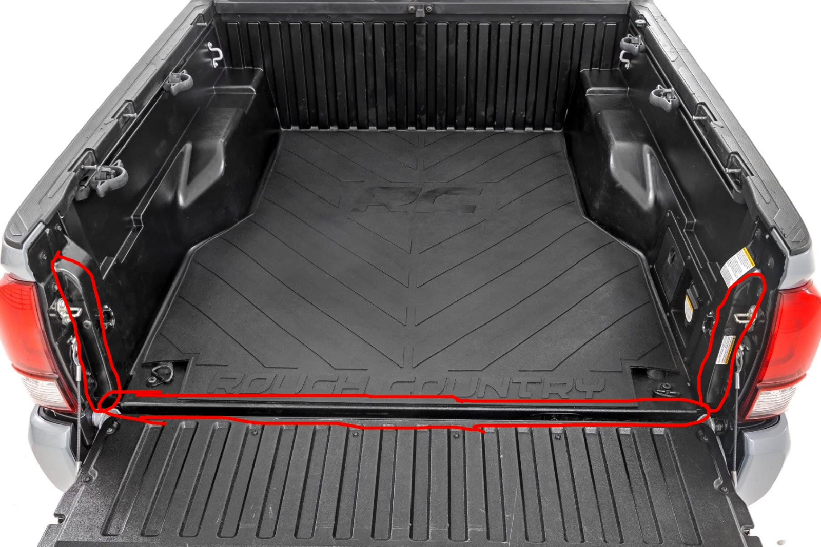 Overhead view of empty red pickup truck bed with black rubber mat and tailgate down, showing storage capacity for overlanding gear