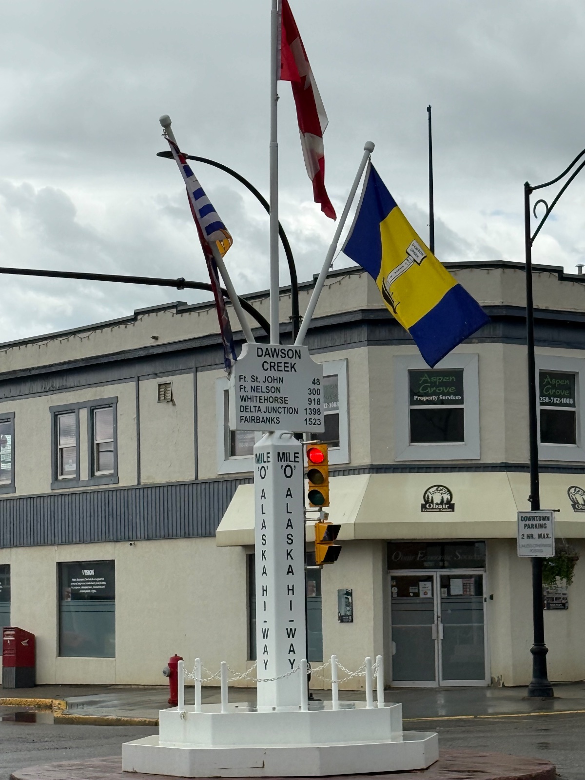 Dawson Creek Mile 0 post with Canadian and local flags at the start of the Alaska Highway in downtown Dawson Creek, British Columbia