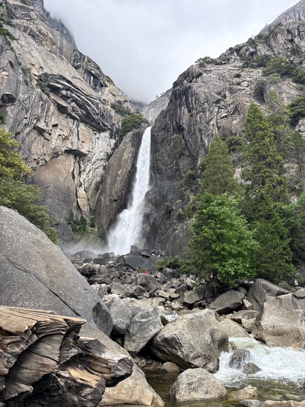 Bridalveil Fall cascades down granite cliffs in Yosemite Valley with hikers on boulder field below