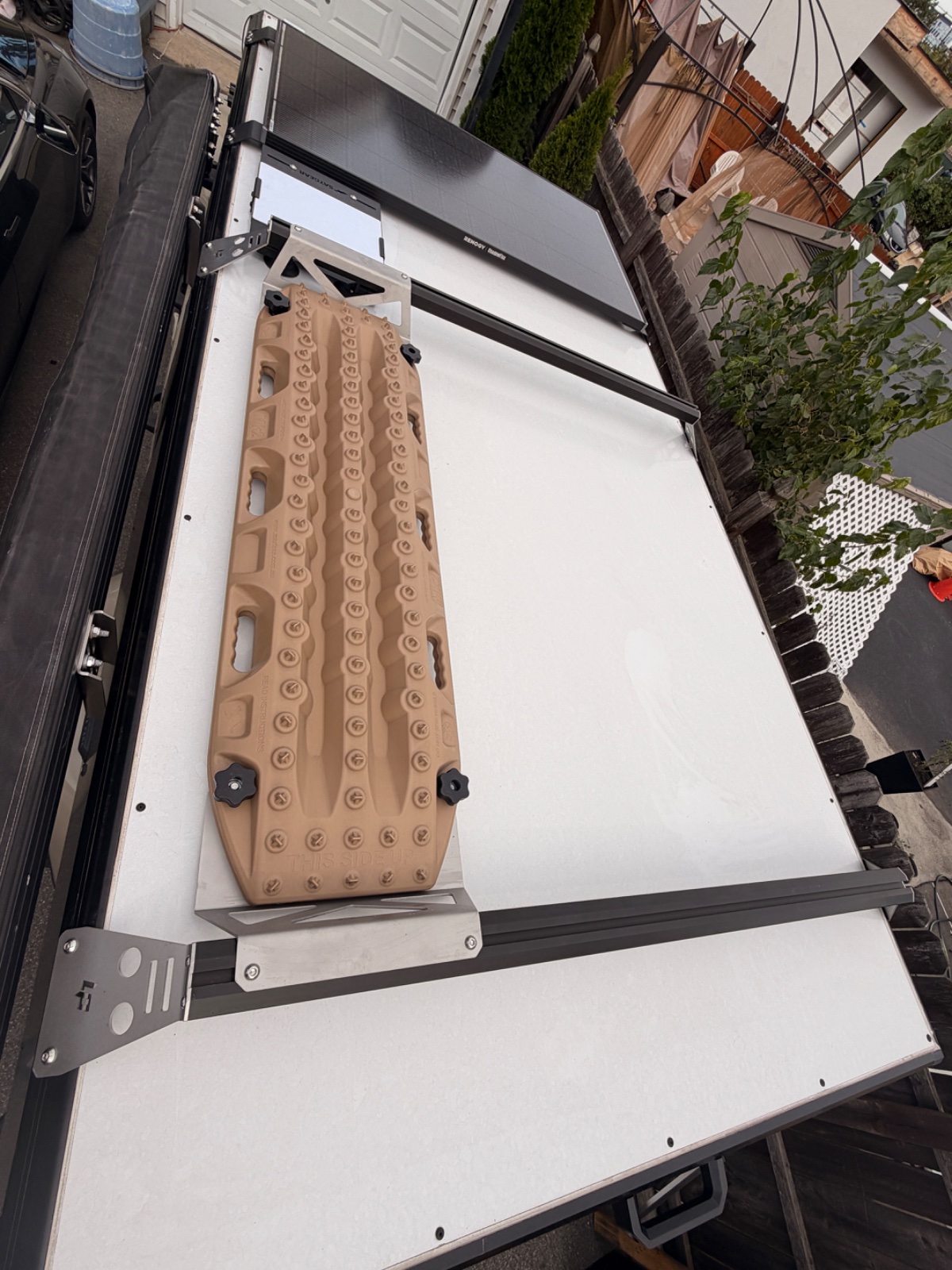 Open truck bed with white tonneau cover and tan egg crate foam organizer mounted on roof rack in residential driveway